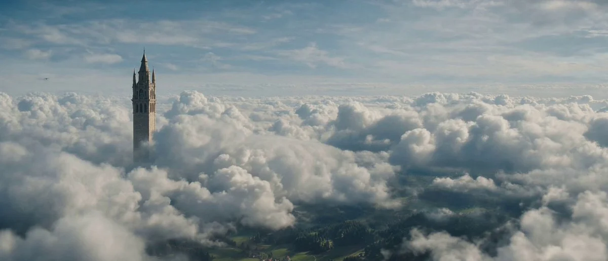 A tower rising above clouds in a wide cinematic landscape.
